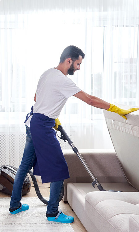 A man in blue apron and yellow gloves cleaning.