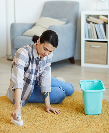 A woman sitting on the floor next to a trash can.