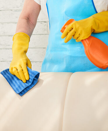 A person in yellow gloves cleaning the seat of an airplane.