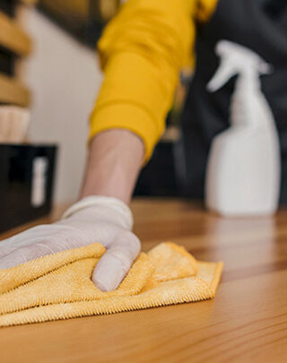 A person wiping down the table with yellow cloth