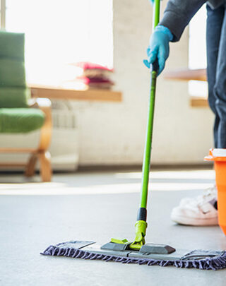 A person in blue gloves mopping the floor.