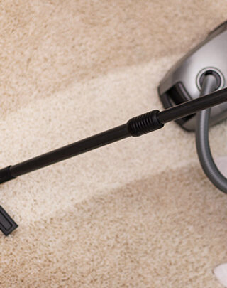 A vacuum cleaner is on the floor of a carpet.