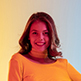 A woman in an orange shirt smiling for the camera.