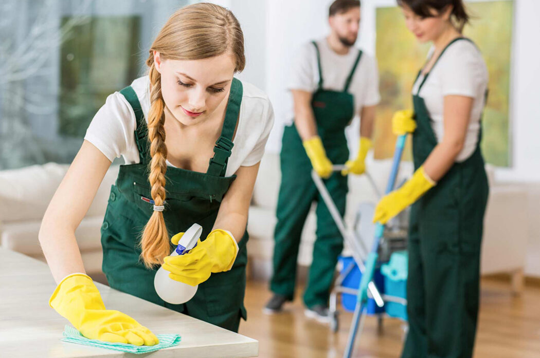 A group of people cleaning the floor with yellow gloves.