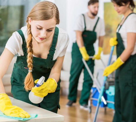 A group of people cleaning the floor with yellow gloves.