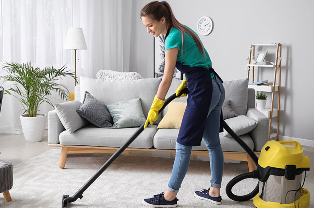 A woman is vacuuming the floor in her living room.